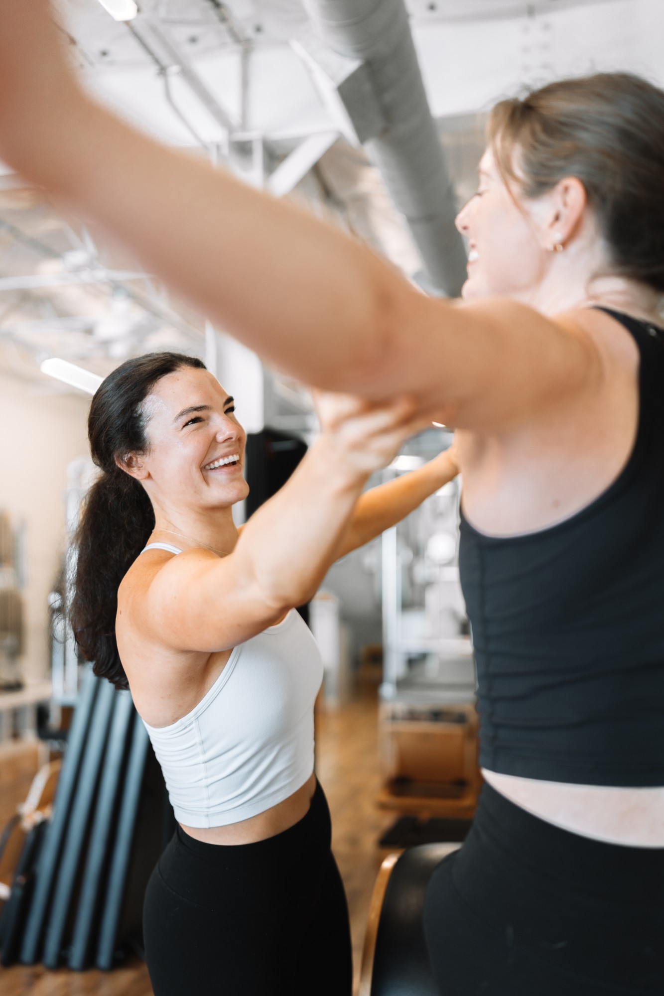 Brett laughing as she guides a client's arm during a Pilates session