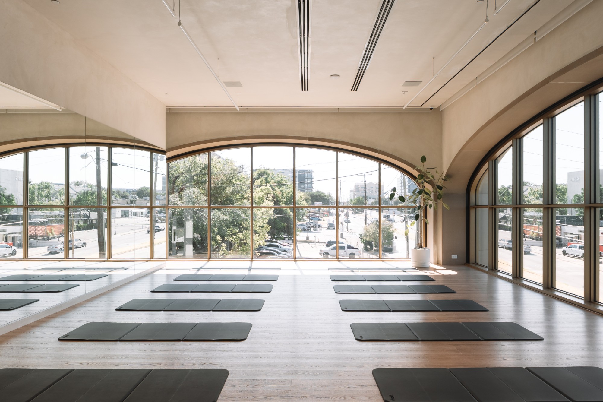 Sunlit O2 Dallas studio with arched windows and mats on the floor